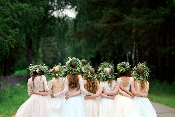 An image of bridesmaids from the back arm in arm